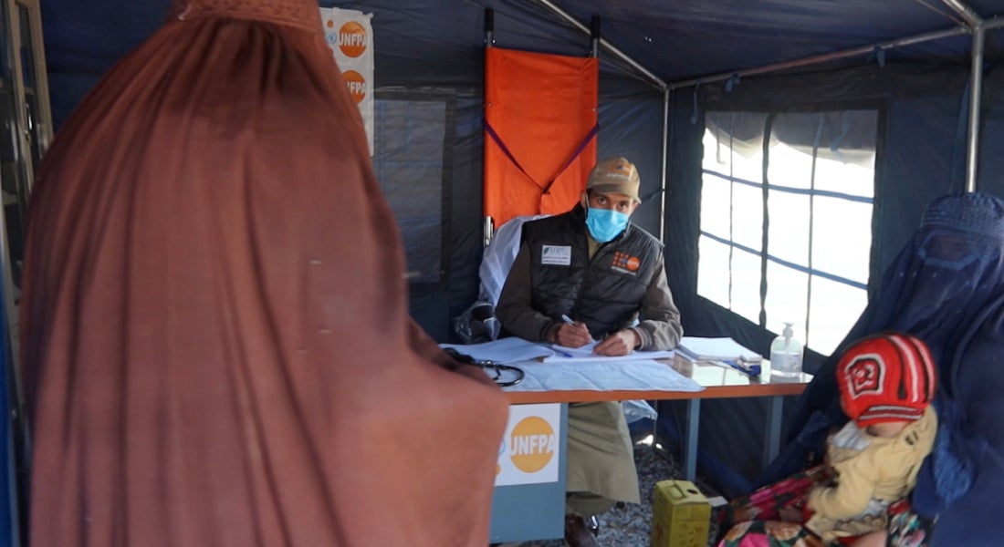 The head doctor at the Torkham reception centre clinic prescribes reproductive health medicines to a mother.